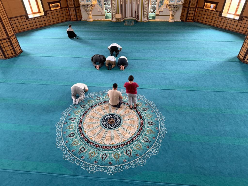 A group of worshippers in prayer inside a beautifully decorated karachi mosque.
