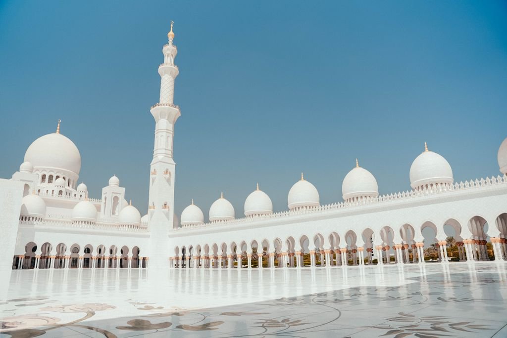 Beautiful view of Abu Dhabi Mosque's white domes and minaret under a clear sky.